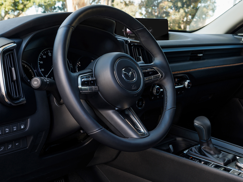 Close-up of the steering wheel and dashboard of a Mazda CX-50, highlighting the modern, minimalist design with easy-to-reach controls.