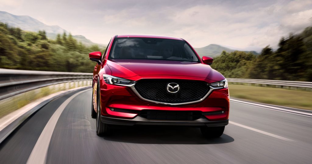 A red Mazda CX-5 driving on the highway.