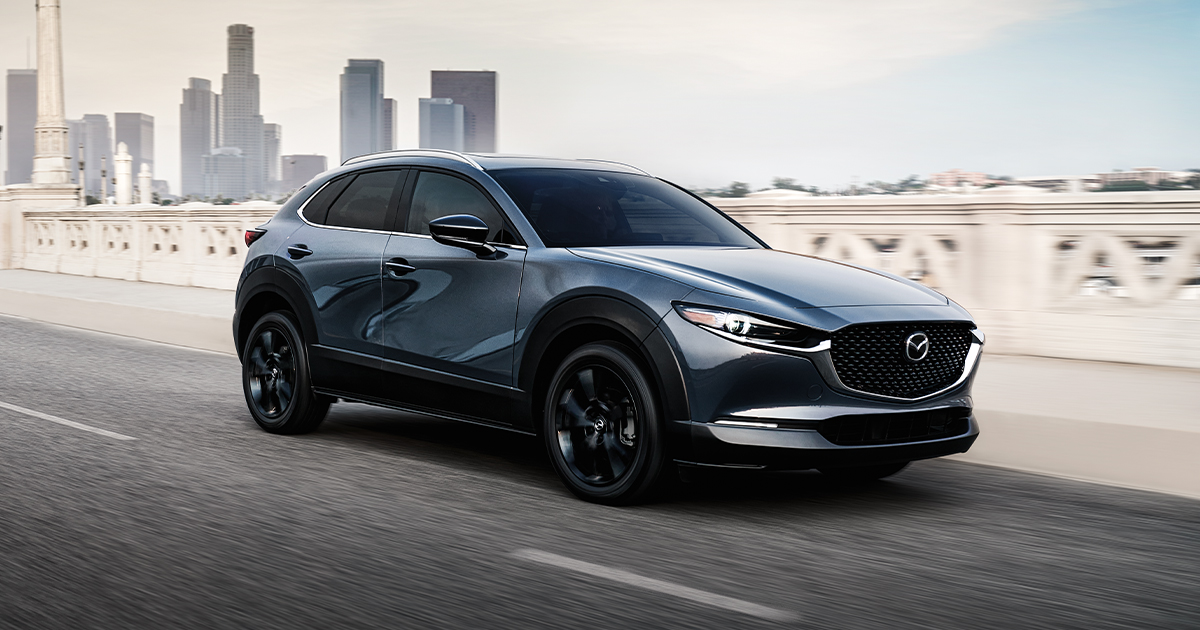 A Mazda CX-30 driving down the highway leaving a city.