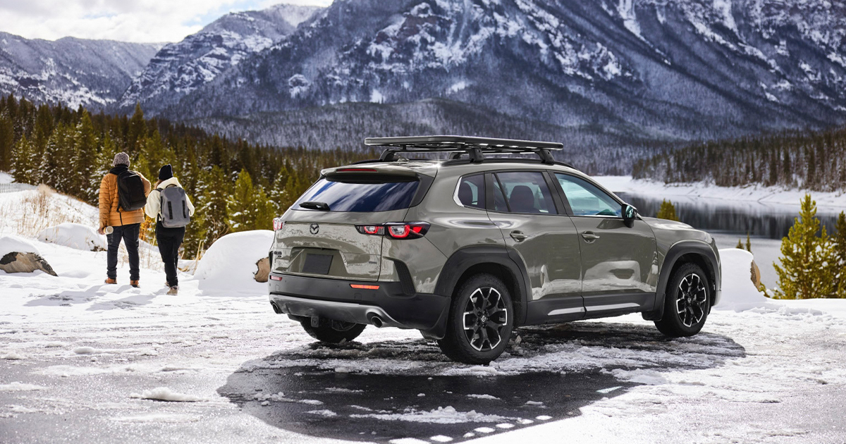 A Mazda CX-50 parked on ice with a mountains in the distance