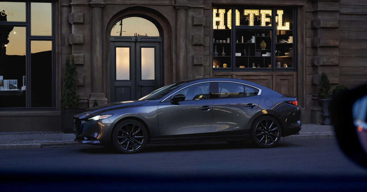 A Mazda3 sedan parked on a city street at night